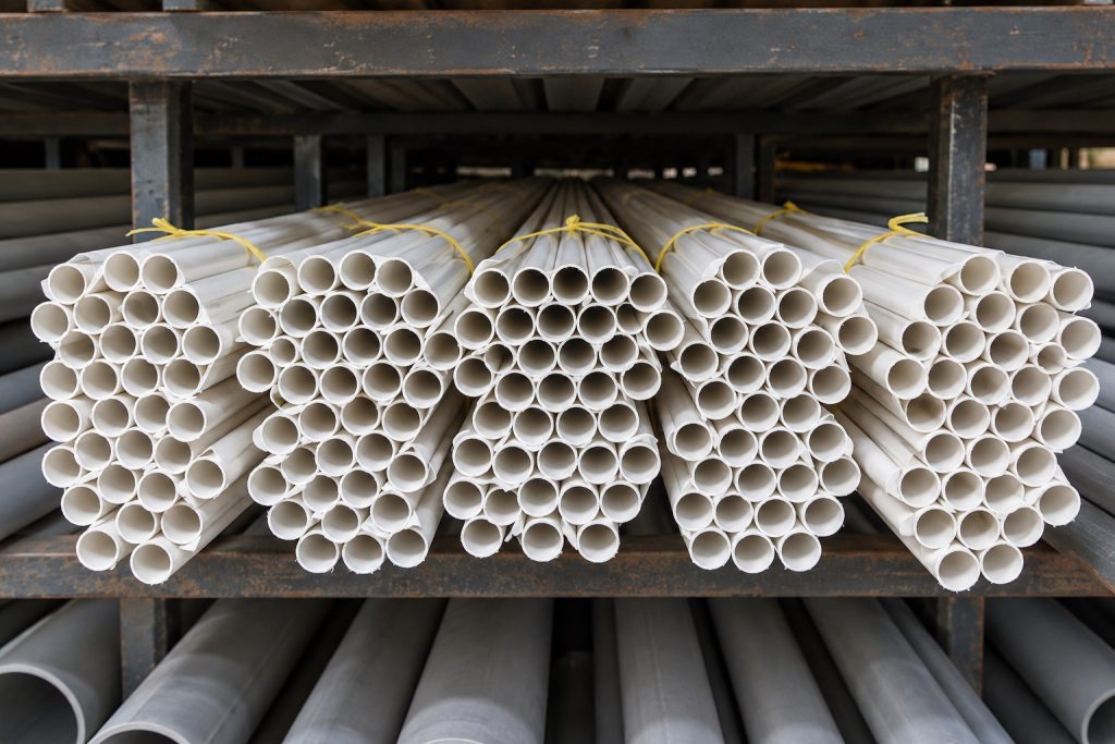 Bundles of thin white conduit tubes tied with yellow string on a rack, seen from the tube ends.