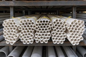 Bundles of thin white conduit tubes tied with yellow string on a rack, seen from the tube ends.