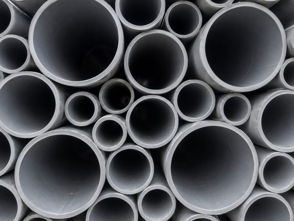 The open ends of grey PVC pipes of many diameters stacked together.