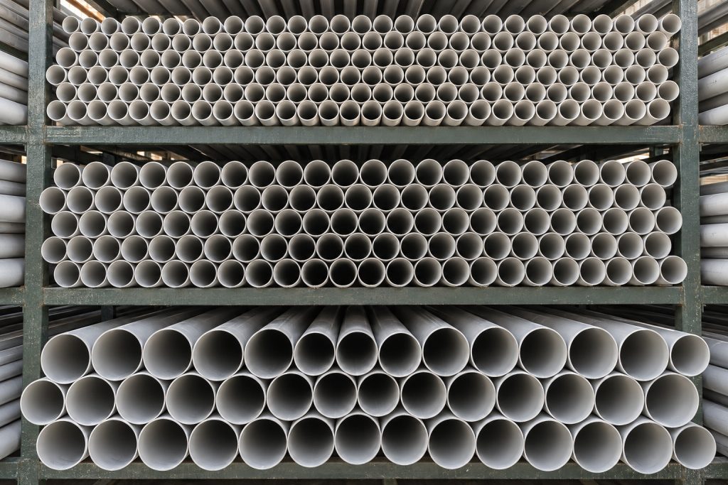 Grey PVC pipes stacked in a steel rack, one size on each level, seen from the pipe ends.