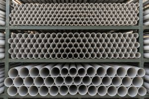 Grey PVC pipes stacked in a steel rack, one size on each level, seen from the pipe ends.